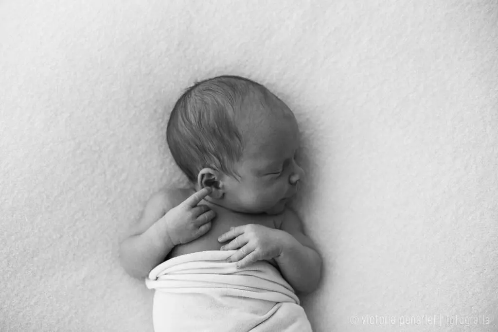 bebé durmiendo sobre un puf envuelto en una muselina